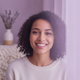 A smiling young woman in her late 20s, with a warm and approachable expression, conveying happiness and contentment.